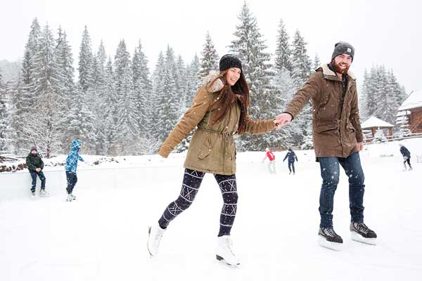 People-skating-winter 人们在户外溜冰场。前景是一对手牵着手的年轻夫妇。