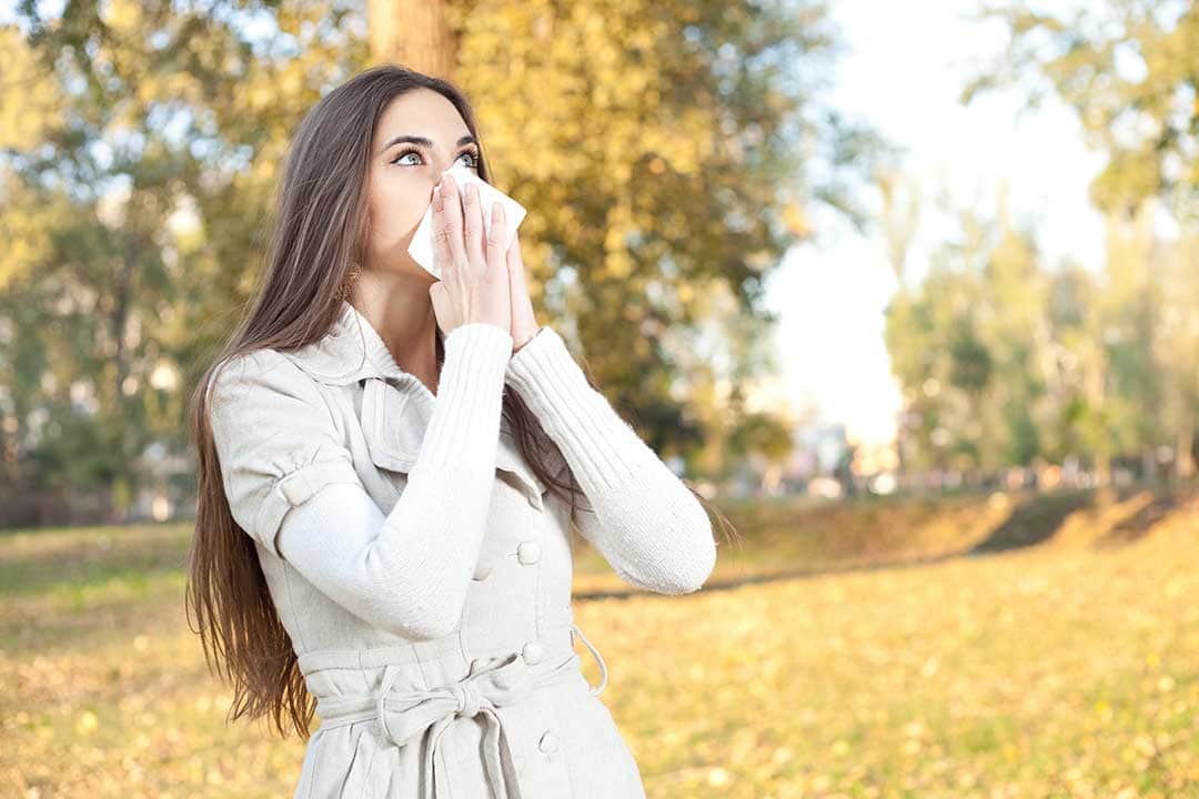 woman-with-hay-allergy 一张对干草过敏的女人用纸巾捂住鼻子的照片。