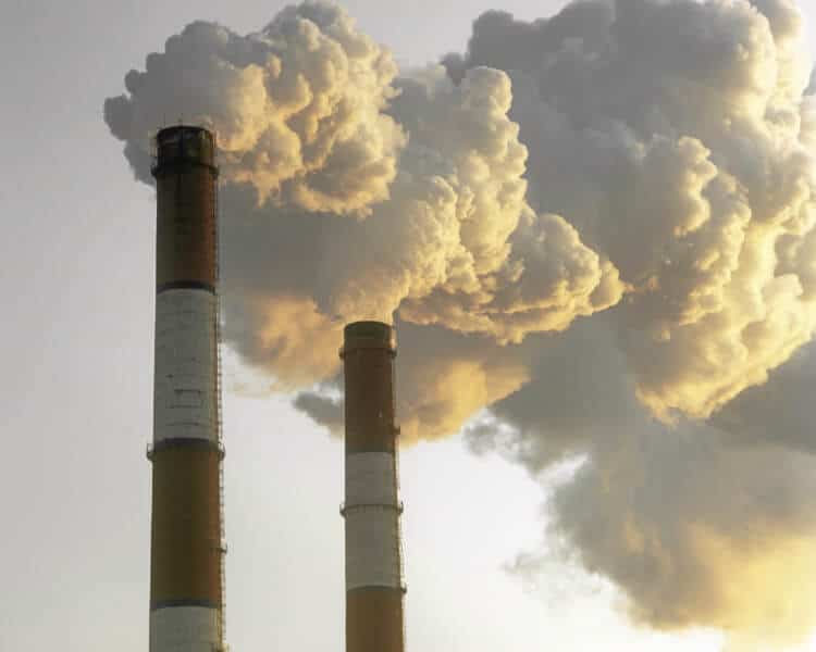 图为一家工厂的两个烟囱向空气中排放污染物。