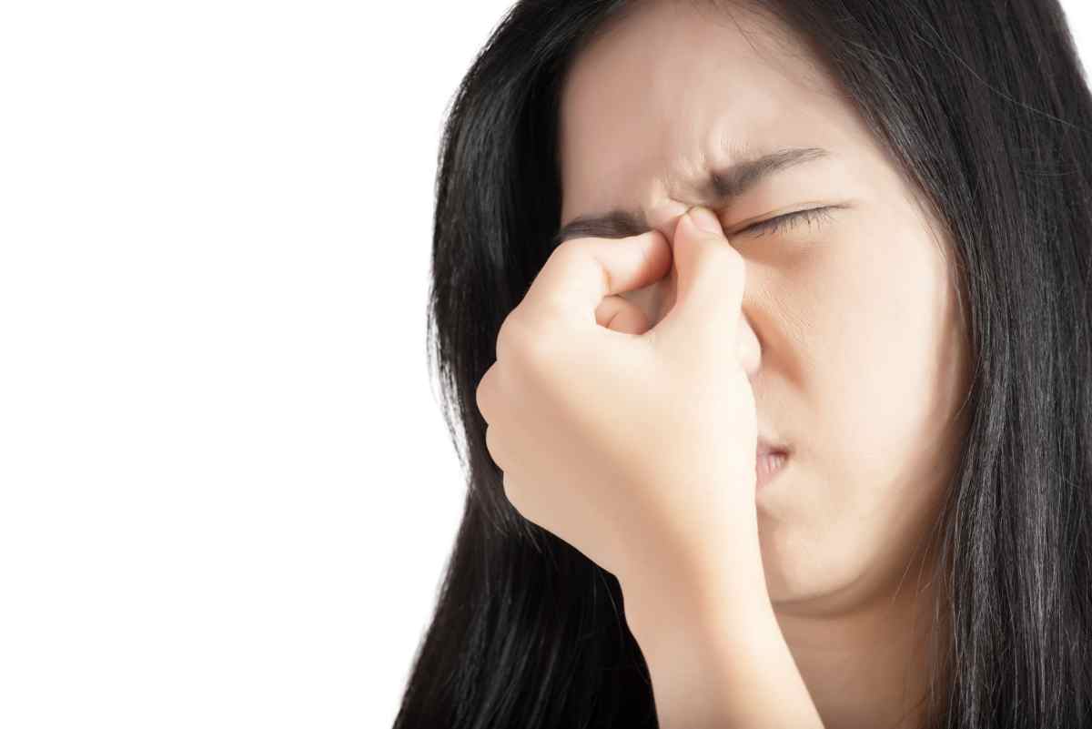 Woman holding her nose because of pain from allergic rhinitis