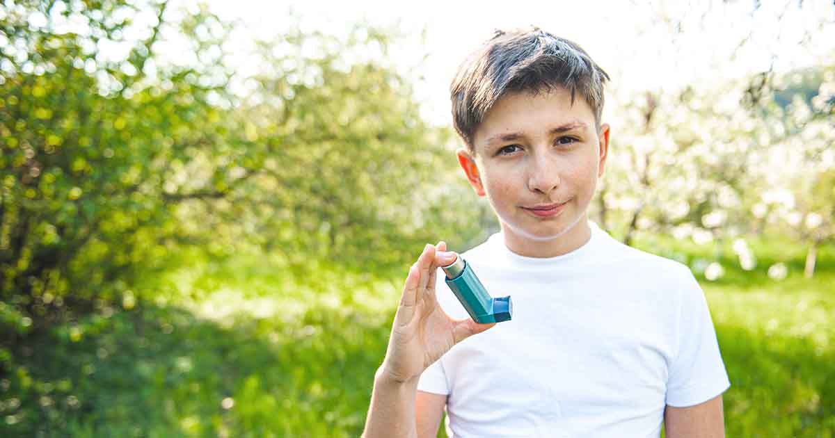Photo of boy holding asthma inhaler outside