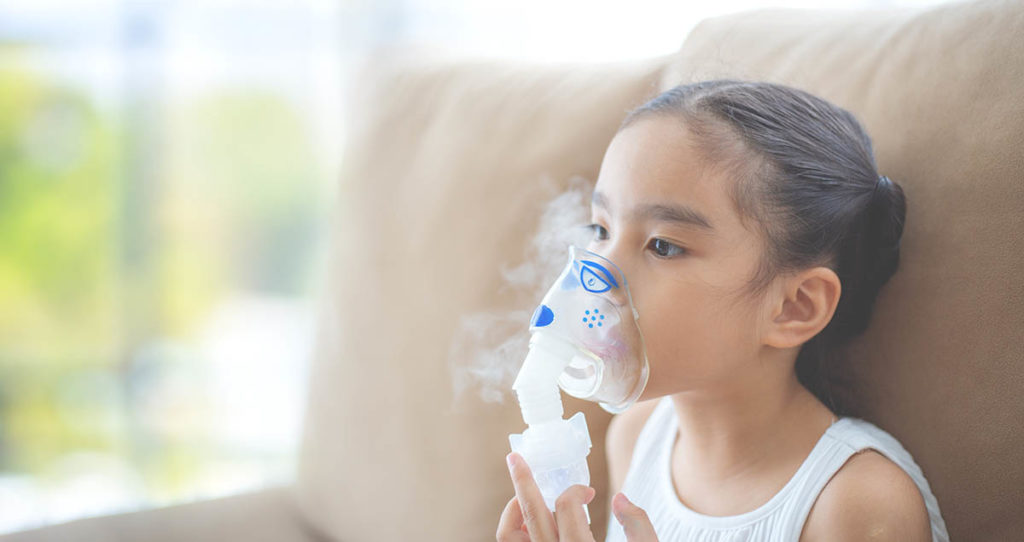 Child patient inhalation therapy by the mask of inhaler with soft stream smoke from bronchodilator.
