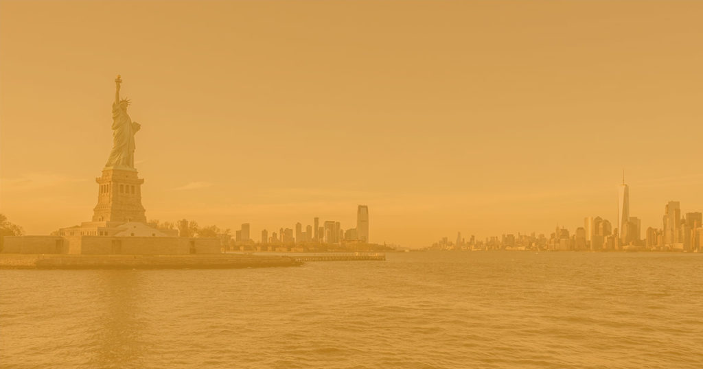 View of Statue of Liberty in New York, from the Hudson Bay. The air is orange and thick with smoke from the Canadian wildfires.