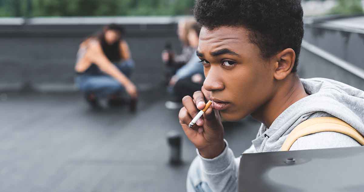 Young black man smoking cigarette outside
